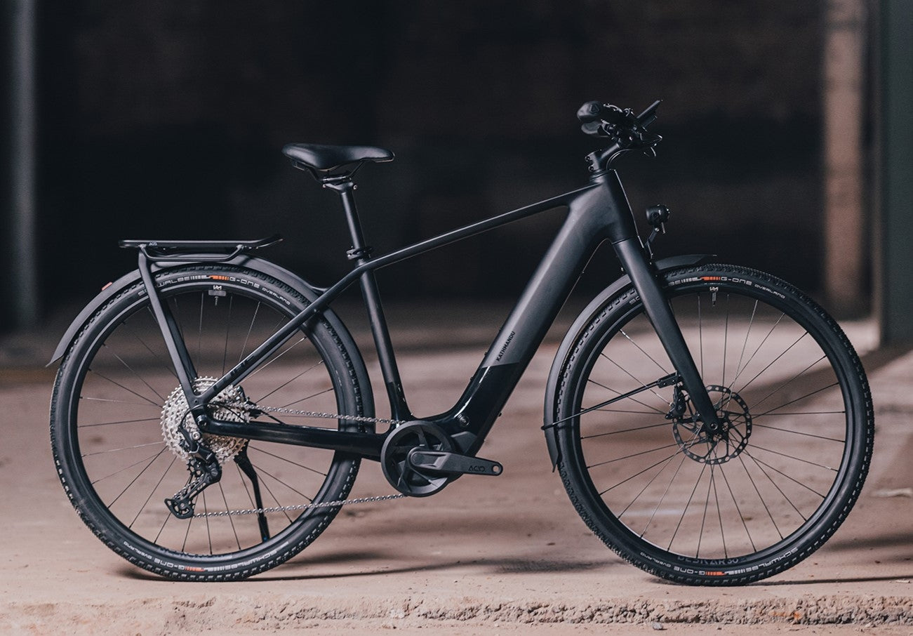 Schwarzes E-Bike Cube Kathmandu Hybrid mit Gepäckträger, ideal für Stadtfahrten und Touren.