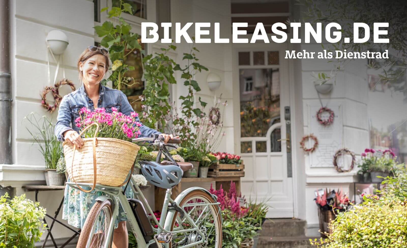 Frau mit Fahrrad und Blumenkorb vor Blumenladen, Schild "BIKELEASING.DE - Mehr als Dienstrad" im Hintergrund.